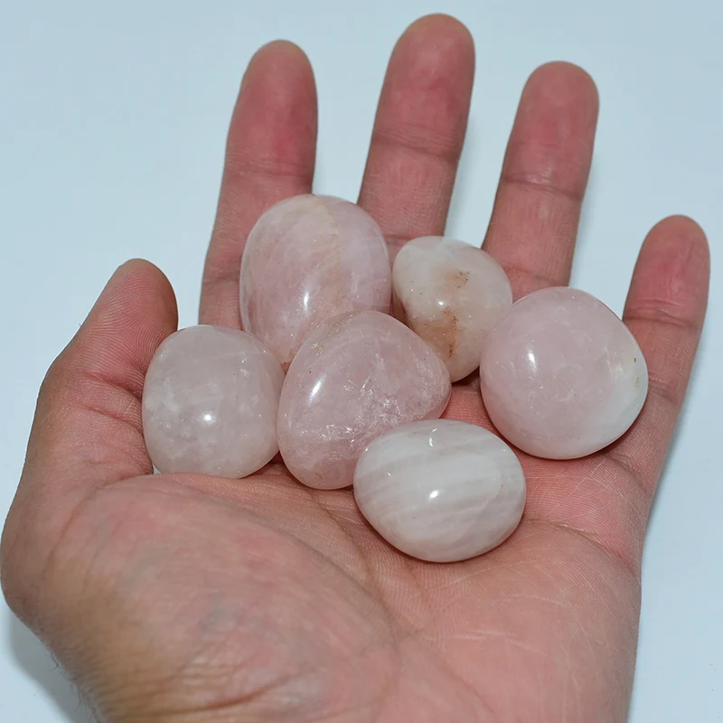 rose quartz tumbled stones wholesale shown in hand for size reference