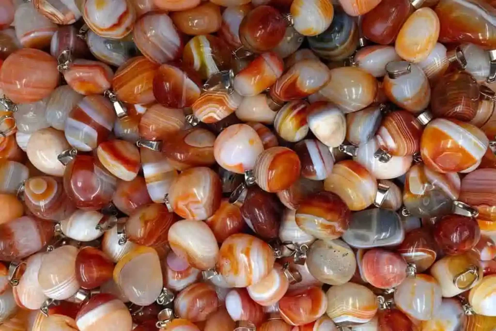 Polished tumbled Carnelian Agate stones in a mix of red and translucent orange hues.