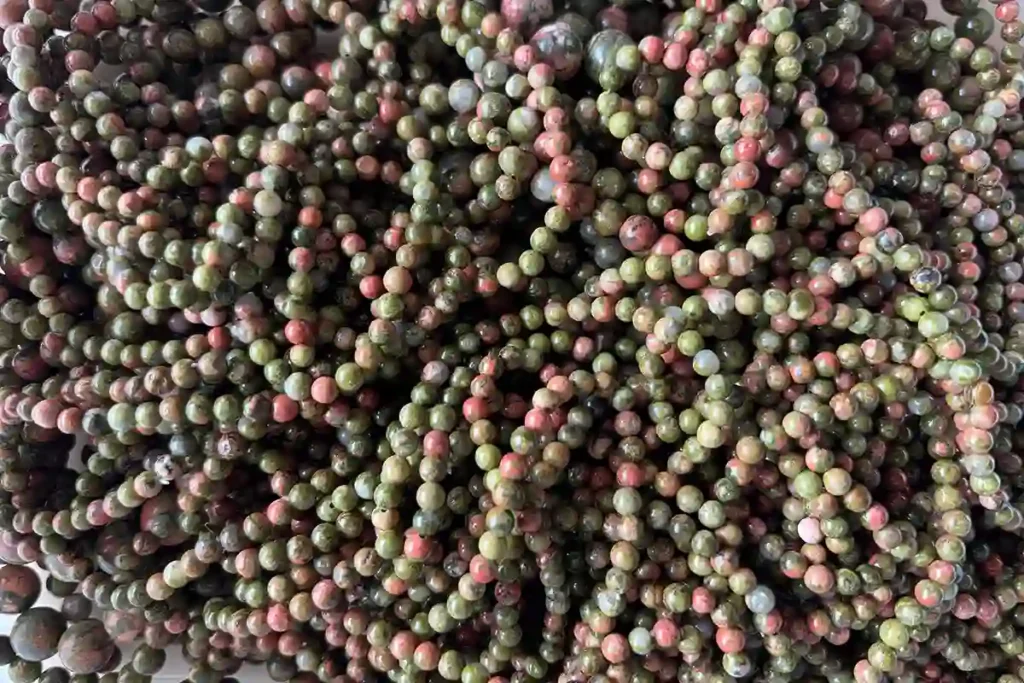 A pile of Unakite Bracelet beads for wholesale, showcasing the deep Unakite meaning of balance and growth.
