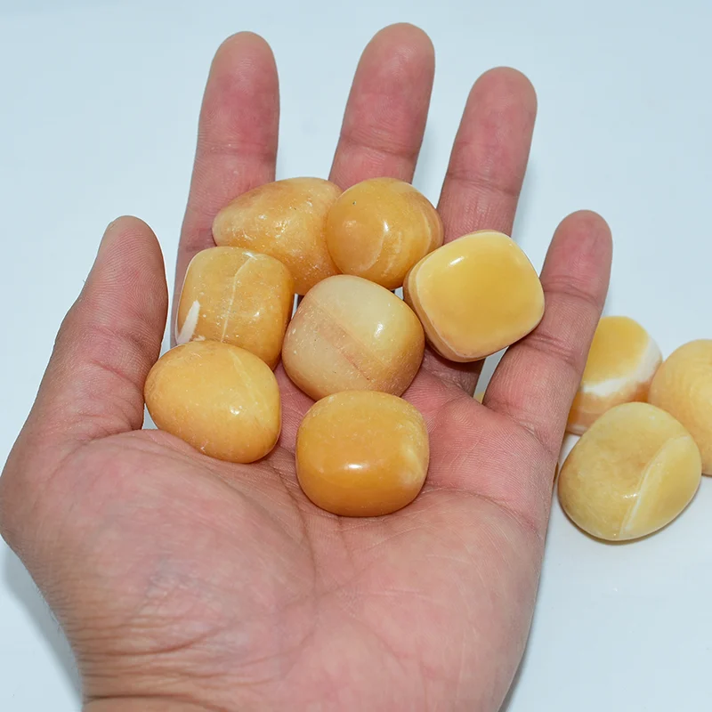 Yellow Calcite Tumbled Stone Wholesale held in hand showing 20-30mm size