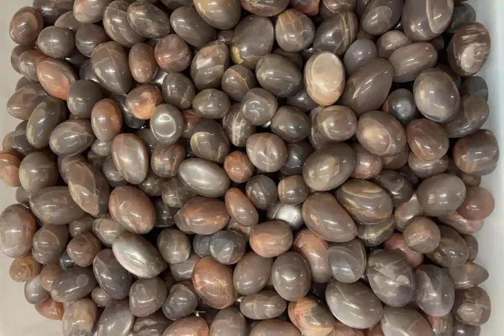 Black moonstone tumbled stones with natural brown and gray tones, illustrating Moonstone Benefits for crystal collections