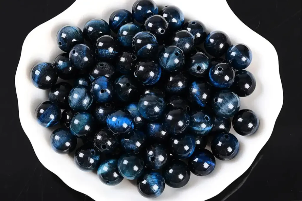 Blue Tigers Eye Meaning – loose blue tiger eye round beads showing dark blue chatoyancy