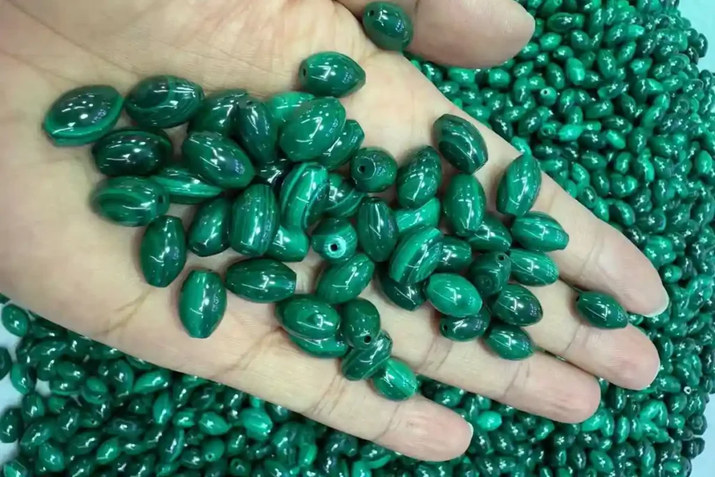 Malachite drop-shaped beads held by hand for jewelry making – Malachite Benefits