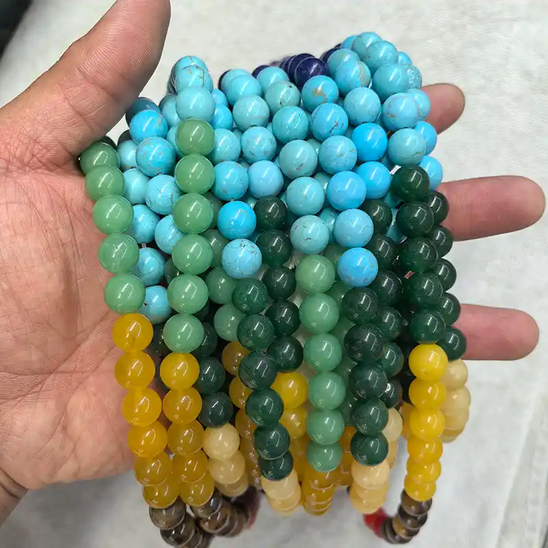 Chakra Beads Wholesale – 10 mm seven-color bead strands displayed in a hand