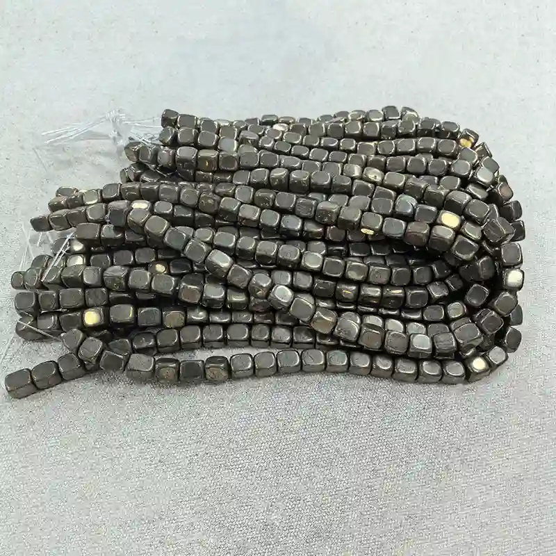 8x10mm Pyrite Beads Wholesale – bundled metallic gray freeform bead strands on a light background