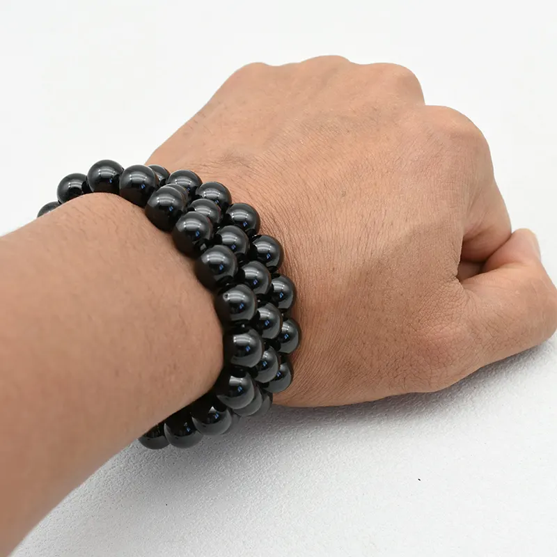 Black Spinel Bracelets Wholesale – polished black round bead bracelet worn on a wrist.