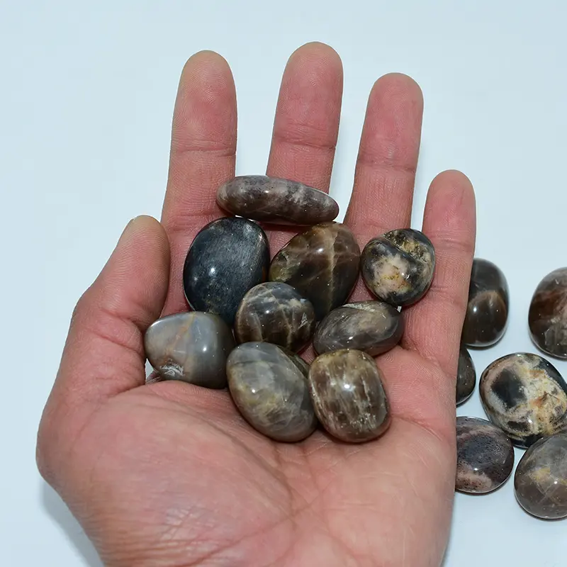 Black Sunstone Tumbled Stone Wholesale – bulk selection of polished stones displayed in an open hand