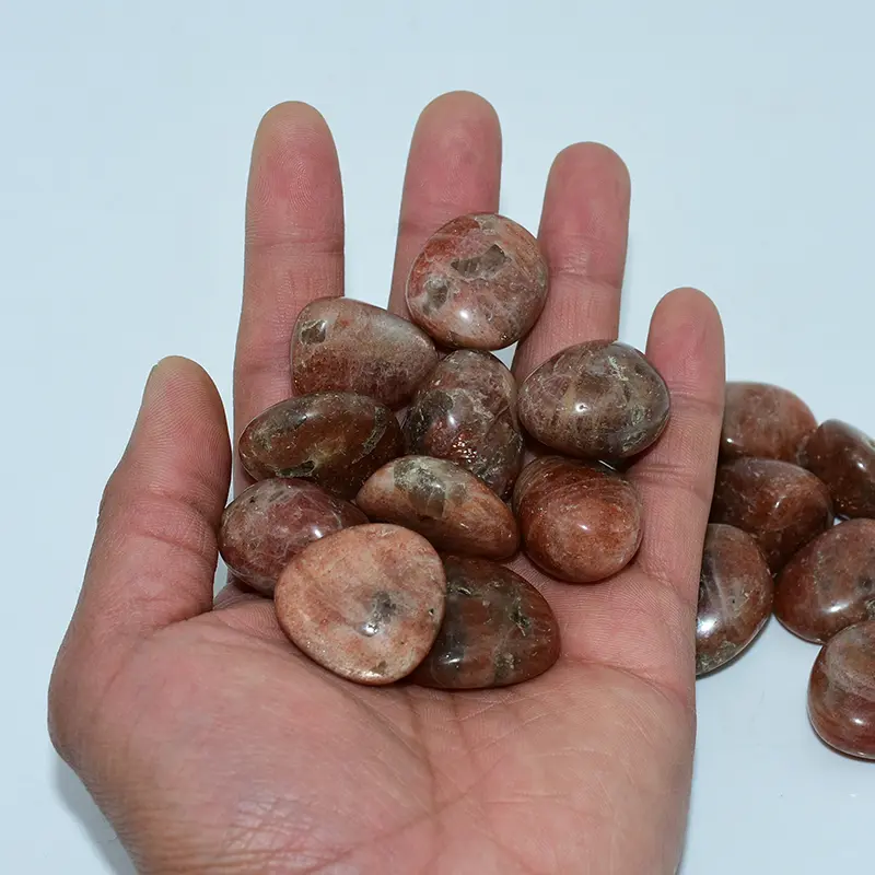 Golden Sunstone Tumbled Stone Wholesale – assorted rounded stones held in a hand