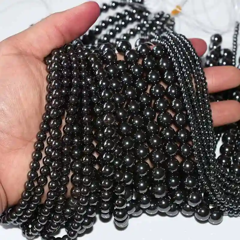 Hematite Beads Wholesale – multiple dark polished bead strands held in one hand