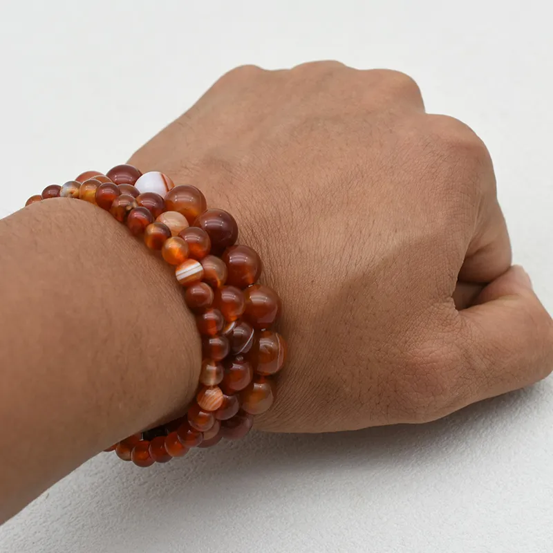 Carnelian Bracelet Wholesale showing red and orange beaded bracelets stacked on a wrist