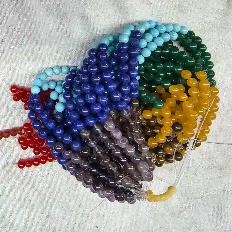 Chakra Beads Wholesale – close-up of bundled multicolor strands with red string ends