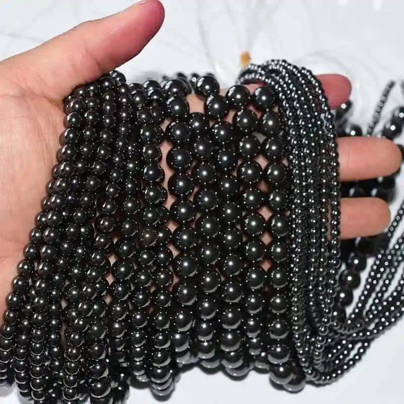 Hematite Beads Wholesale – dark metallic bead strands draped across an open palm